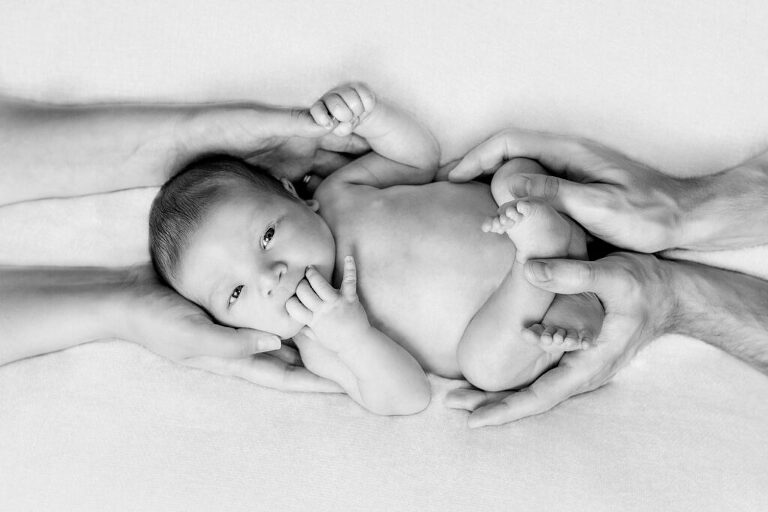 Baby being held by his parents. Learning to take photographs of your newborn baby during lockdown.