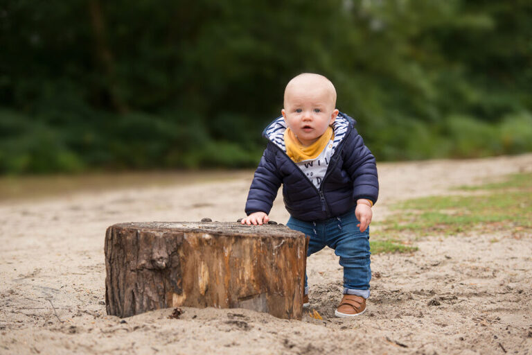 Baby holding onto a log at 9 months old is another good option when choosing the best age for newborn photography and older baby photoshoots.